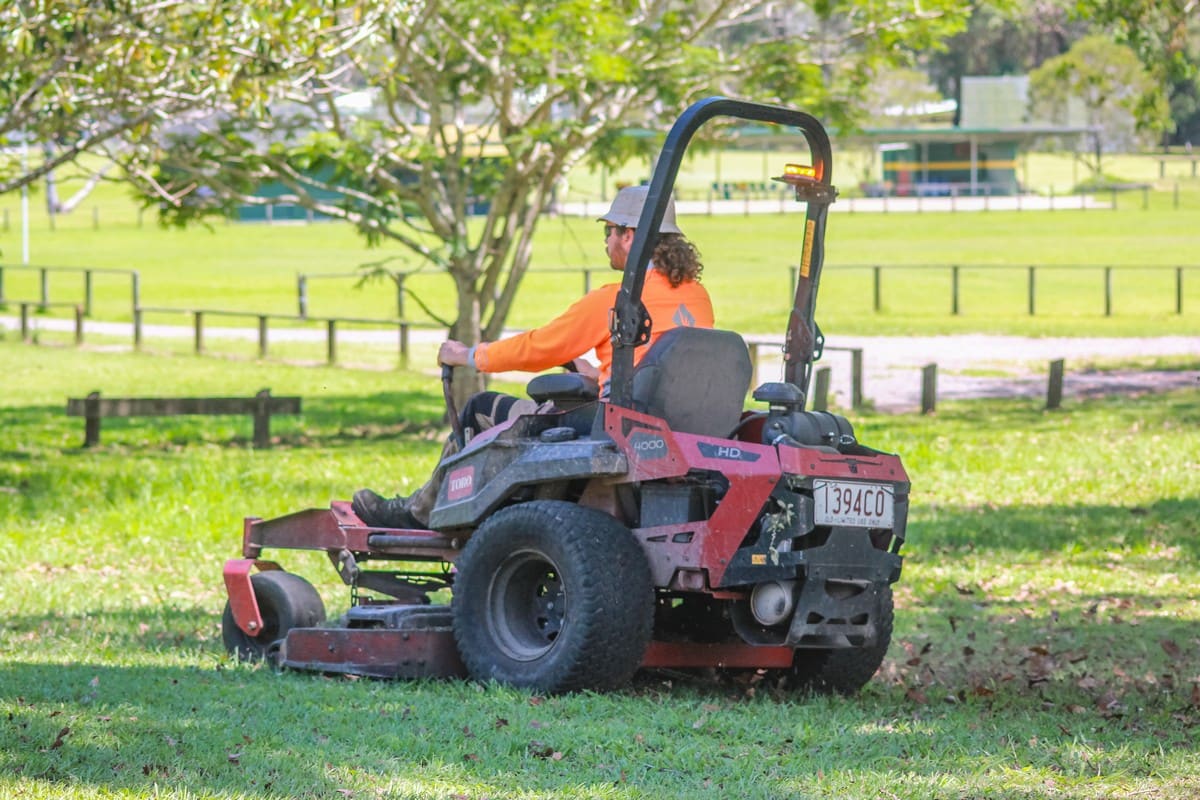 Crew on ride-on mower at council sportsfield
