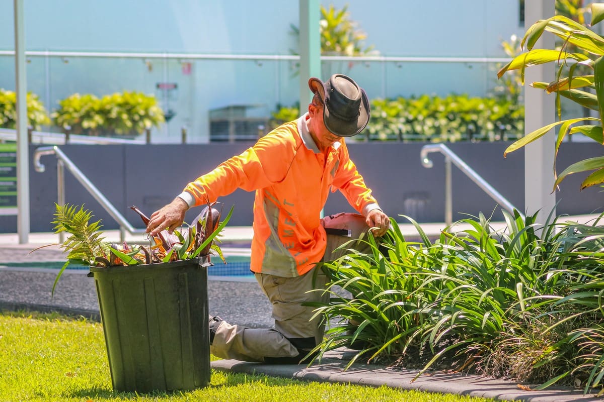 Crew member weeding and maintaining garden bed