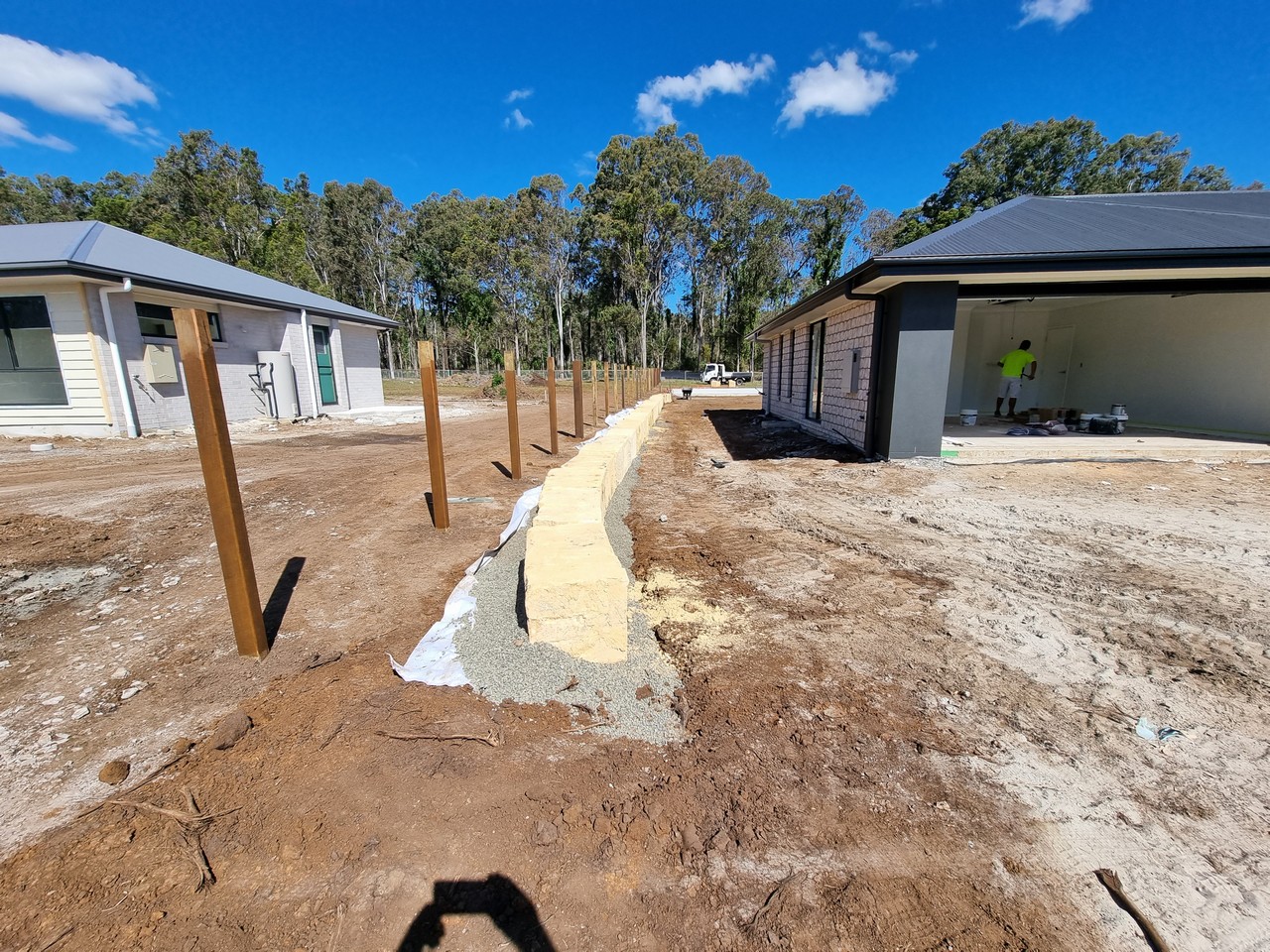 Retaining wall and fence post installation between homes