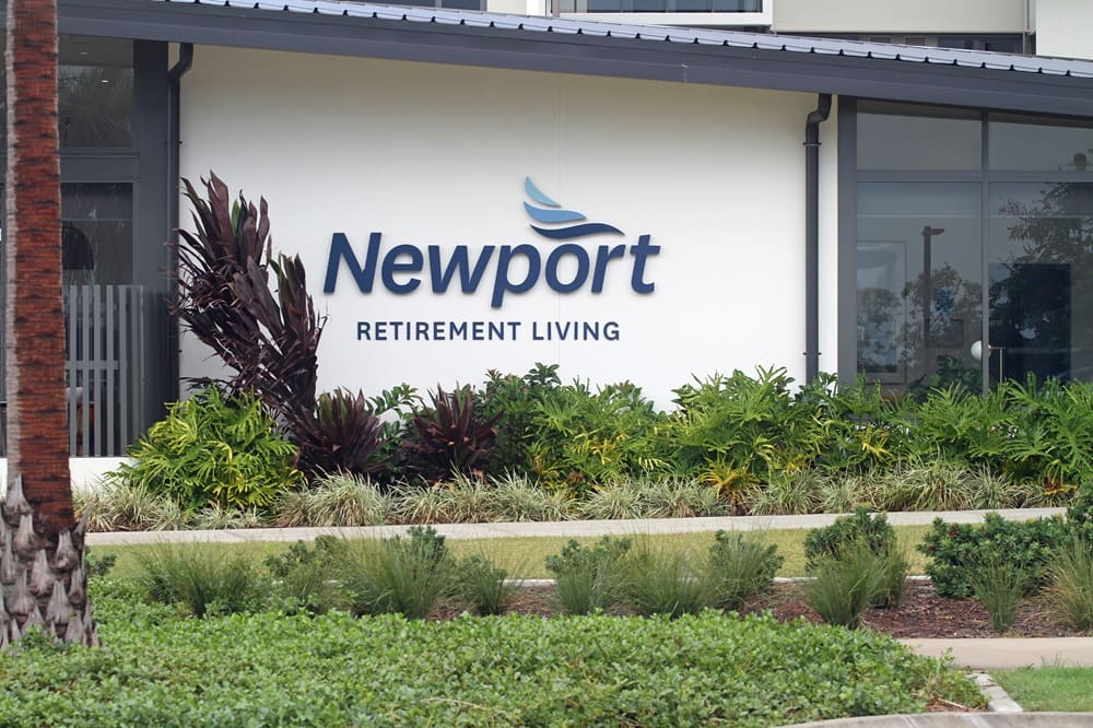 Newport Retirement Living signage with maintained garden beds and landscaping