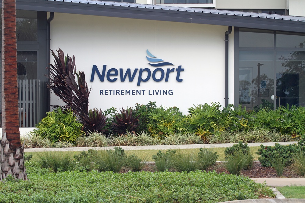 Newport Retirement Living signage with maintained garden beds and landscaping